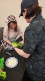 Class runner Emily Key helps to guide a participant through making sure that the top and bottom halves of the box are connected together at the hinge point.